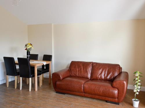 a living room with a leather couch and a table at Oak Cottage in Winthorpe
