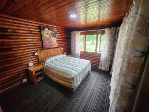a bedroom with a bed in a log cabin at Plettenberg, a Forever Resort in Plettenberg Bay
