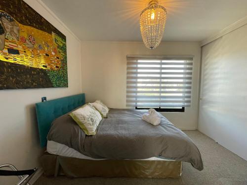 a bedroom with a bed with a chandelier and a window at Departamento con Vista al Mar en Pichilemu in Pichilemu