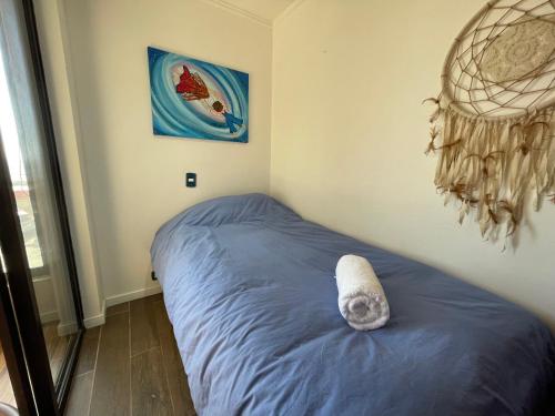 a bed in a bedroom with a painting on the wall at Departamento con Vista al Mar en Pichilemu in Pichilemu