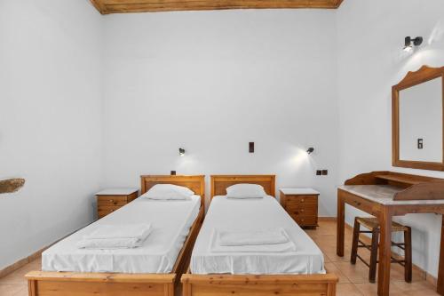 two beds in a room with a table and a mirror at Countryside Apartment 2 with Shared Swimming Pool in Chania Town