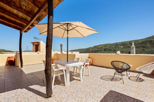 a patio with a table and chairs and an umbrella at Countryside Apartment 2 with Shared Swimming Pool in Chania Town