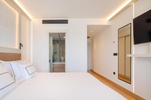 a white bedroom with a large bed and a television at Melia Alicante in Alicante