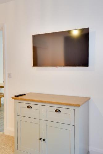 a tv on a wall above a white counter at No 3 at The Rocketroom Apartments in Berwick-Upon-Tweed
