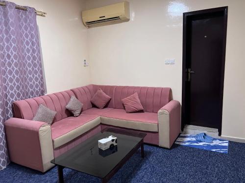 a living room with a pink couch and a table at Queen Cleopatra suite in Ajman 