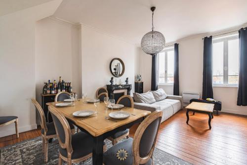 un salon avec une table et un canapé dans l'établissement l'Hôtel des Ventes Reims Chativesle, à Reims