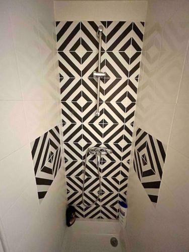 La salle de bains est pourvue d'un mur noir et blanc à motifs. dans l'établissement Chez Jean, Studio cosy, à Toulouse