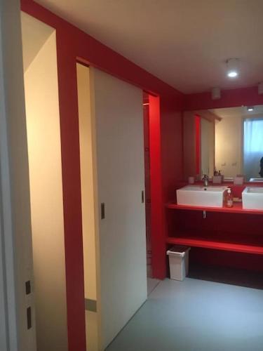 La salle de bains est pourvue de 2 lavabos et d'un mur rouge. dans l'établissement Loft-Maison de ville-Parking-Famille Pas de fête, à Athis-Mons