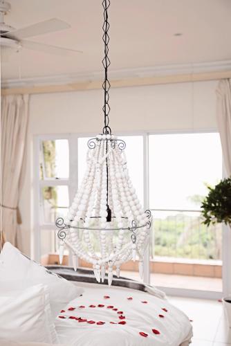 a chandelier hanging over a bed in a bedroom at Umthunzi Hotel and Conference in Umtentweni
