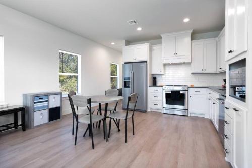 a kitchen with white cabinets and a table and chairs at Brand New Modern Getaway on Private Land! in Tulsa