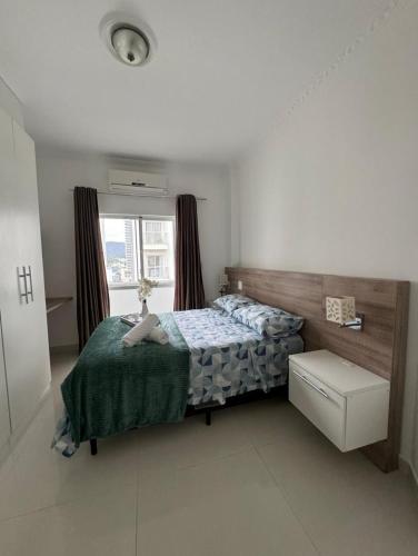 a bedroom with a bed and a window at Apartamento 01suite e um quarto in Balneário Camboriú
