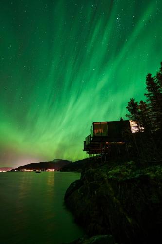 a house under the aurora borealis on the shore of a lake at Yttervik in Mo i Rana