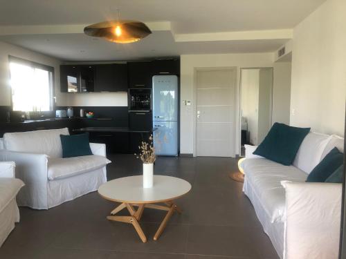 een woonkamer met twee witte banken en een tafel bij Eluard 04 - Domaine d'Arca - PORTO-VECCHIO - Rez de jardin - 4 à 6 pers in Porto-Vecchio