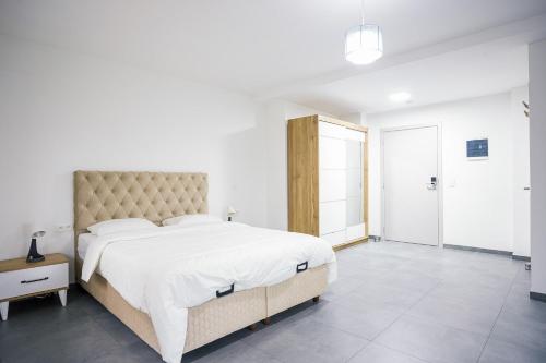 a white bedroom with a large bed and a large window at Résidence la floraison in Brussels