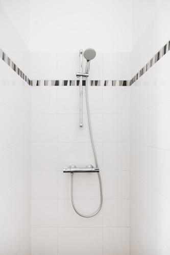 La salle de bains est pourvue d'une douche et de carrelage blanc. dans l'établissement La Maison D'Olivier, à Mesnard-la-Barotière