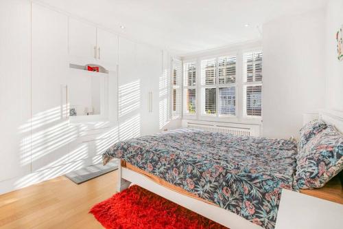 ein weißes Schlafzimmer mit einem Bett und einem roten Teppich in der Unterkunft 5-Bed Family Retreat in Chiswick in London