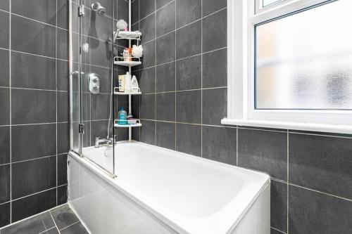 ein Badezimmer mit weißer Badewanne und Fenster in der Unterkunft 5-Bed Family Retreat in Chiswick in London