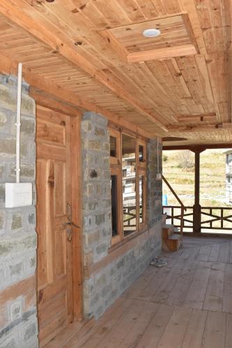 a room with a stone wall and a wooden ceiling at Riverstone Heights in Jibhi