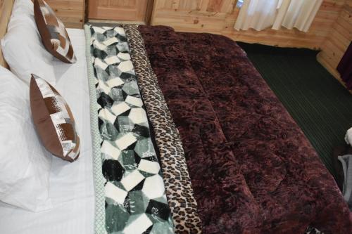 a bed with a cheetah blanket and shoes on it at Riverstone Heights in Jibhi