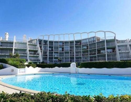 ein großes Gebäude mit einem großen Pool davor in der Unterkunft Studio Belles Plages 1 ère ligne climatisé in La Grande-Motte