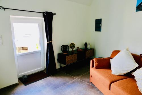 a living room with an orange couch and a window at Le gîte 24 proche du Futuroscope - Jacuzzi compris in Beaumont