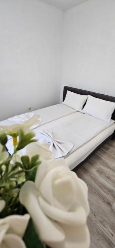 a bed with white sheets and a bouquet of flowers at Apartman Mima in Sanski most