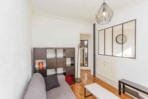 un salon avec un canapé et une horloge au mur dans l'établissement Cocon parisien lumineux central, à Paris