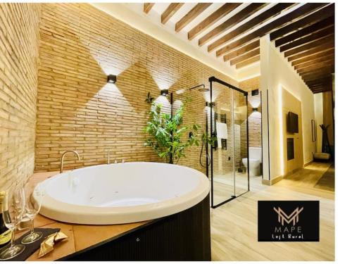 a bathroom with a large tub in a brick wall at Winahost Algar Rural in Algar