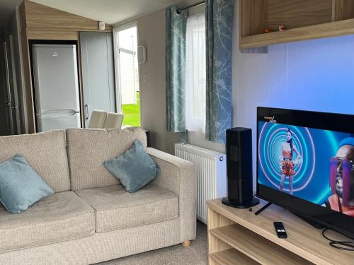 a living room with a couch and a flat screen tv at Surfside Bliss - Cayton Bay Park caravan in Scarborough