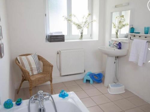 a bathroom with a tub and a sink and a chair at Les Bergeronnettes in Camors