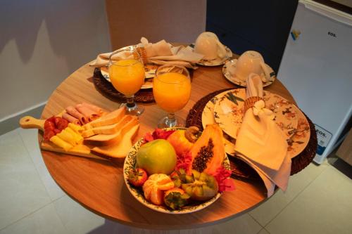 a wooden table with plates of food and glasses of orange juice at Pipa Day Flats in Pipa