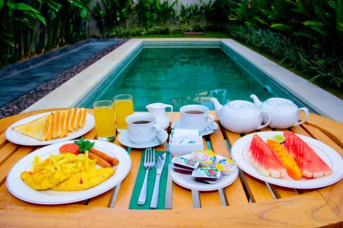 een tafel met borden eten naast een zwembad bij Delu Villas & Suite in Kerobokan