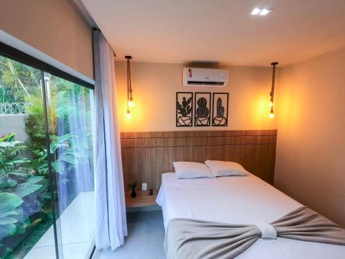 a bedroom with two beds and a large window at Pipa Day Flats in Pipa