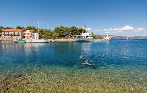 two people swimming in a body of water with boats at 3 Bedroom Beautiful Home In Veli Iz in Veli Iž