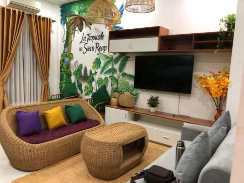 a living room with two couches and a flat screen tv at La Tropicale de Siem Reap in Phumĭ Kruŏs