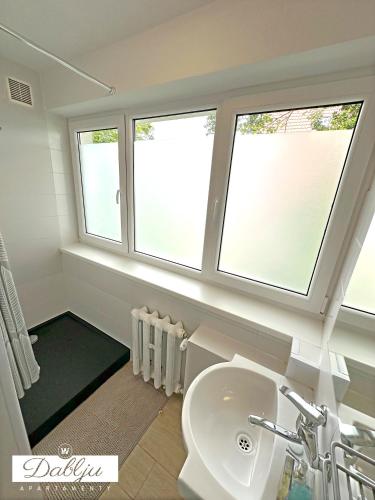 a bathroom with a sink and two windows at W Dablju - Apartementy nad morzem in Władysławowo