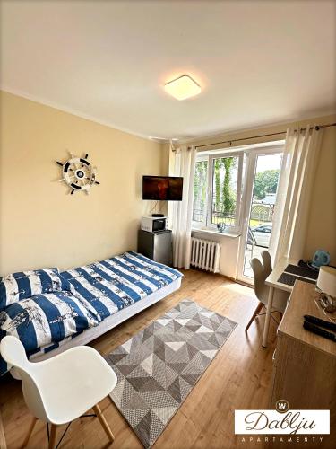 a bedroom with a bed and a desk and a television at W Dablju - Apartementy nad morzem in Władysławowo