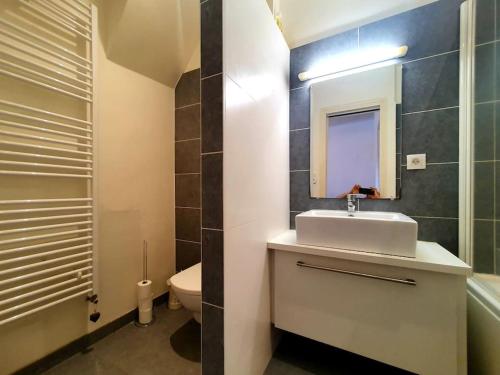 a bathroom with a sink and a toilet and a mirror at La Capitainerie Port du Légué in Plérin