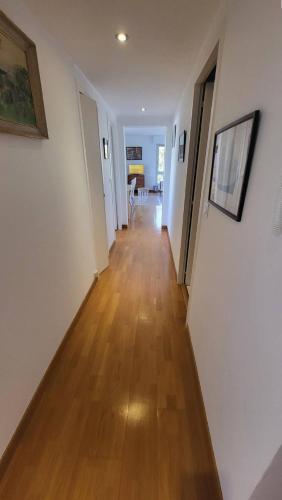 un couloir avec des murs blancs et un parquet en bois dur dans l'établissement Saint jean de Luz, Les Camélias, Appt 4pers, terrasse, à Sainte-Barbe