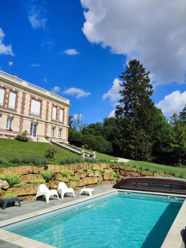 a swimming pool with two chairs and a building at Demeure de la Garenne in Montmirail