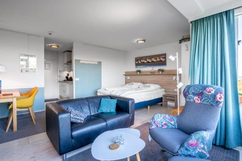 Una sala de estar con un sofá y sillas y una cama. en Appartementencomplex Juliana 68, en De Koog