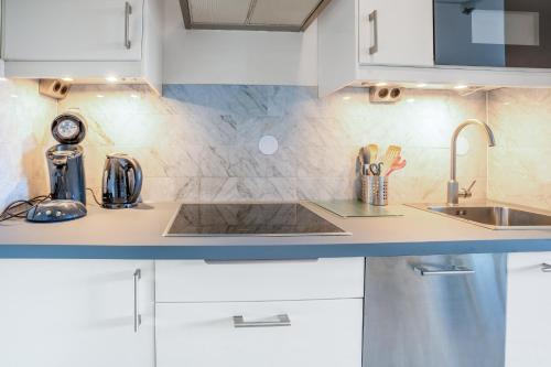 a kitchen with white cabinets and a sink at Appartementencomplex Juliana 68 in De Koog