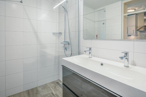 Un baño blanco con lavabo y ducha. en Appartementencomplex Juliana 68, en De Koog