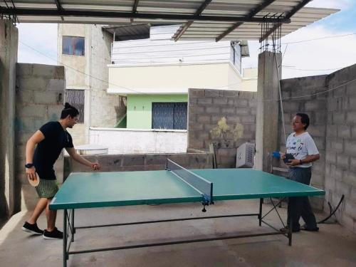 two men are standing around a ping pong table at Mini Suite en el centro de la ciudad in Macará