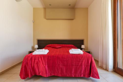 a bedroom with a red bed with towels on it at Lido Marini Rooms Affittacamere B&B in Lido Marini