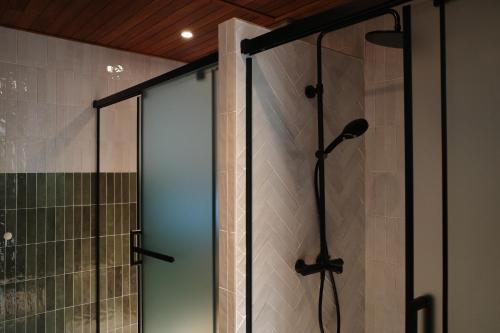 a shower with a glass door in a bathroom at Inn the Midst 淺山深居 in Taitung City