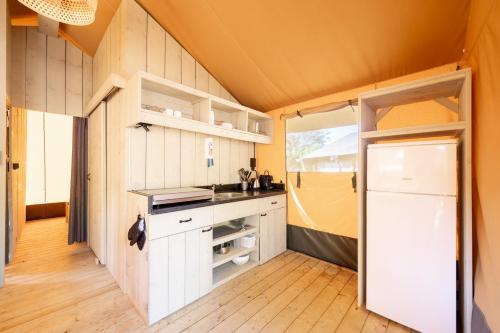 une cuisine avec des armoires blanches et une porte ouverte dans l'établissement Glamping Hautes-Alpes, à Prunières