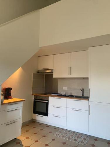 une cuisine avec des armoires blanches et un four à plaques de cuisson dans l'établissement Charmant duplex au calme avec parking, à Sainte-Maxime