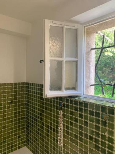 une salle de bain avec une fenêtre et un mur carrelé vert dans l'établissement Charmant duplex au calme avec parking, à Sainte-Maxime