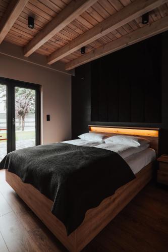 a bedroom with a large bed with a black blanket at Ptasia ferajna - domki całoroczne w Dolinie Baryczy in Milicz